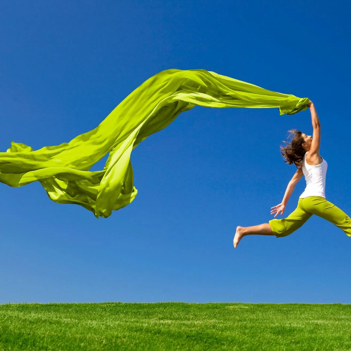 A person jumping and holding a green flowy fabric